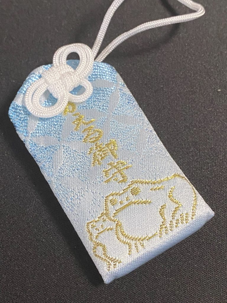 十番稲荷神社のかえる御守。水色にかえるが二匹金色の糸で刺繍されています。
