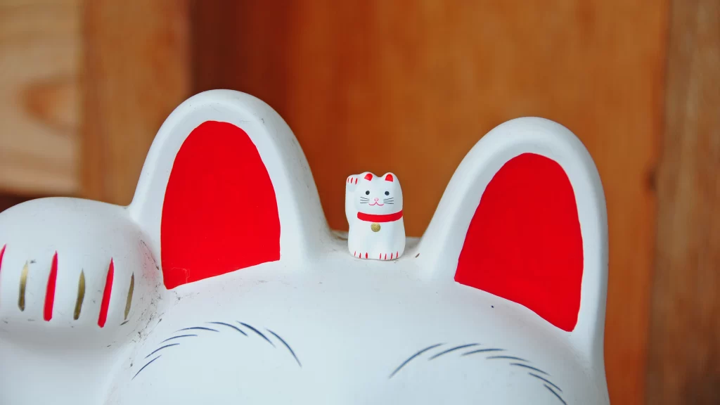 豪徳寺招き猫。大きな招き猫の頭の上に乗る豆サイズ